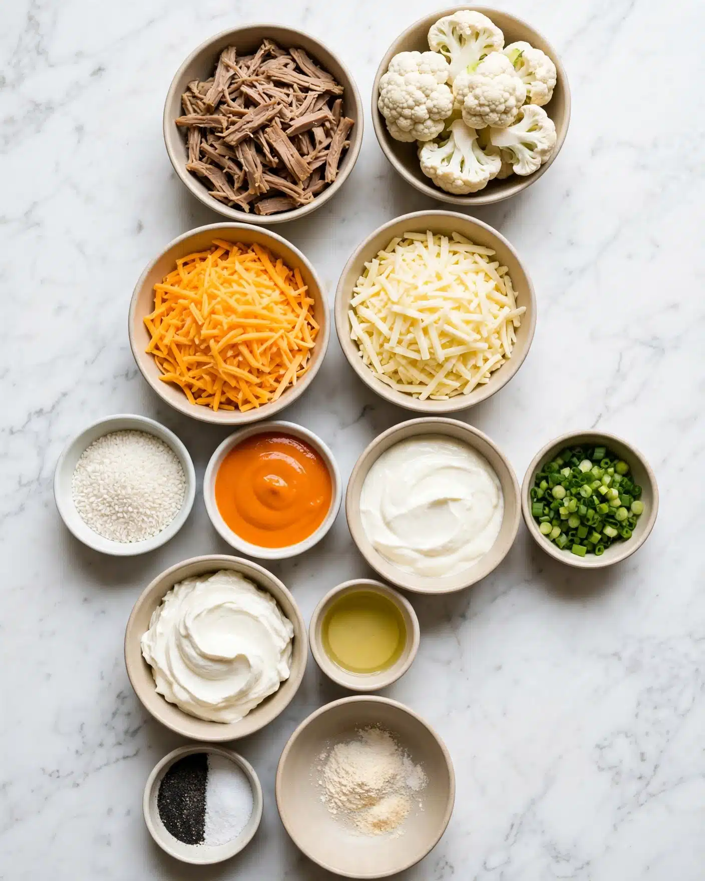 The image shows twelve bowls of different sizes placed on a white marbled surface. The top right bowl is full of white cauliflower florets with a rough texture. To the left, there is another bowl containing shredded cooked light brown meat in thin strips. Moving down, two bowls side by side hold shredded cheese; the left one has bright orange cheese and the right one has pale yellow cheese. Below these, a small white bowl holds white granular grains, and next to it, there is a bowl with bright orange sauce with a smooth surface. Another beige bowl holds a thick white creamy substance, while a smaller bowl near it includes finely chopped green onions. At the bottom left corner, there is a tiny bowl of black and white powder divided into halves, and next to it, a beige bowl contains a small amount of light powder. Above this, a medium bowl holds a thick creamy white substance, and next to it, there is a small cup of light yellow liquid, possibly oil. The bowls are neatly arranged in rows, showing a variety of textures from creamy to grainy and fresh to cooked. photo taken with an iphone --ar 4:5 --v 7