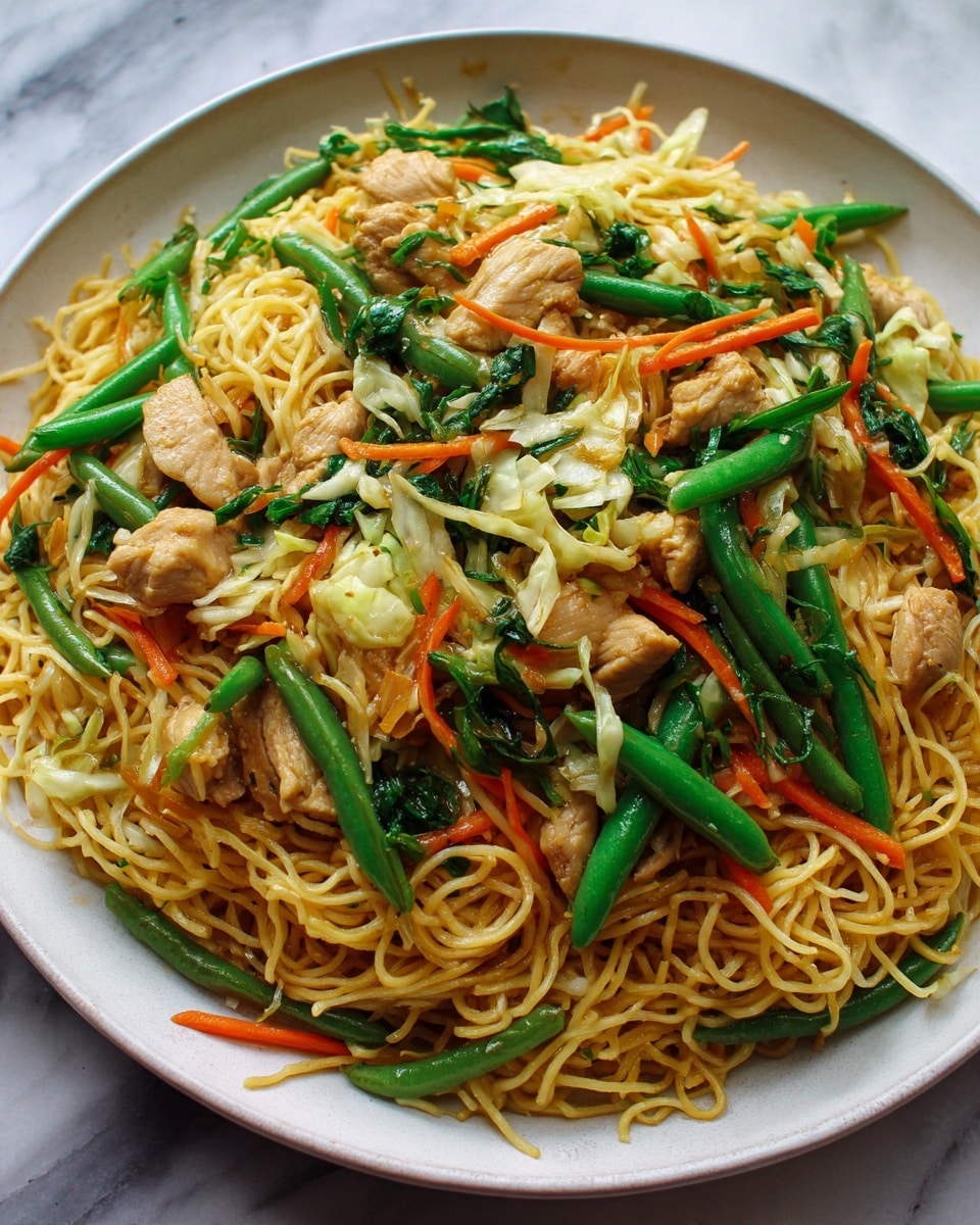 The image shows a close-up of a stir-fried noodle dish with three main layers. The bottom layer is light golden yellow thin noodles, tangled and shiny with sauce. Scattered through the noodles are thin strips of orange carrot and light green cabbage, adding color and texture. On top, there are pieces of light brown cooked chicken chunks mixed with bright green beans and wilted dark green leafy vegetables. The dish sits on a white marbled surface. photo taken with an iphone --ar 4:5 --v 7